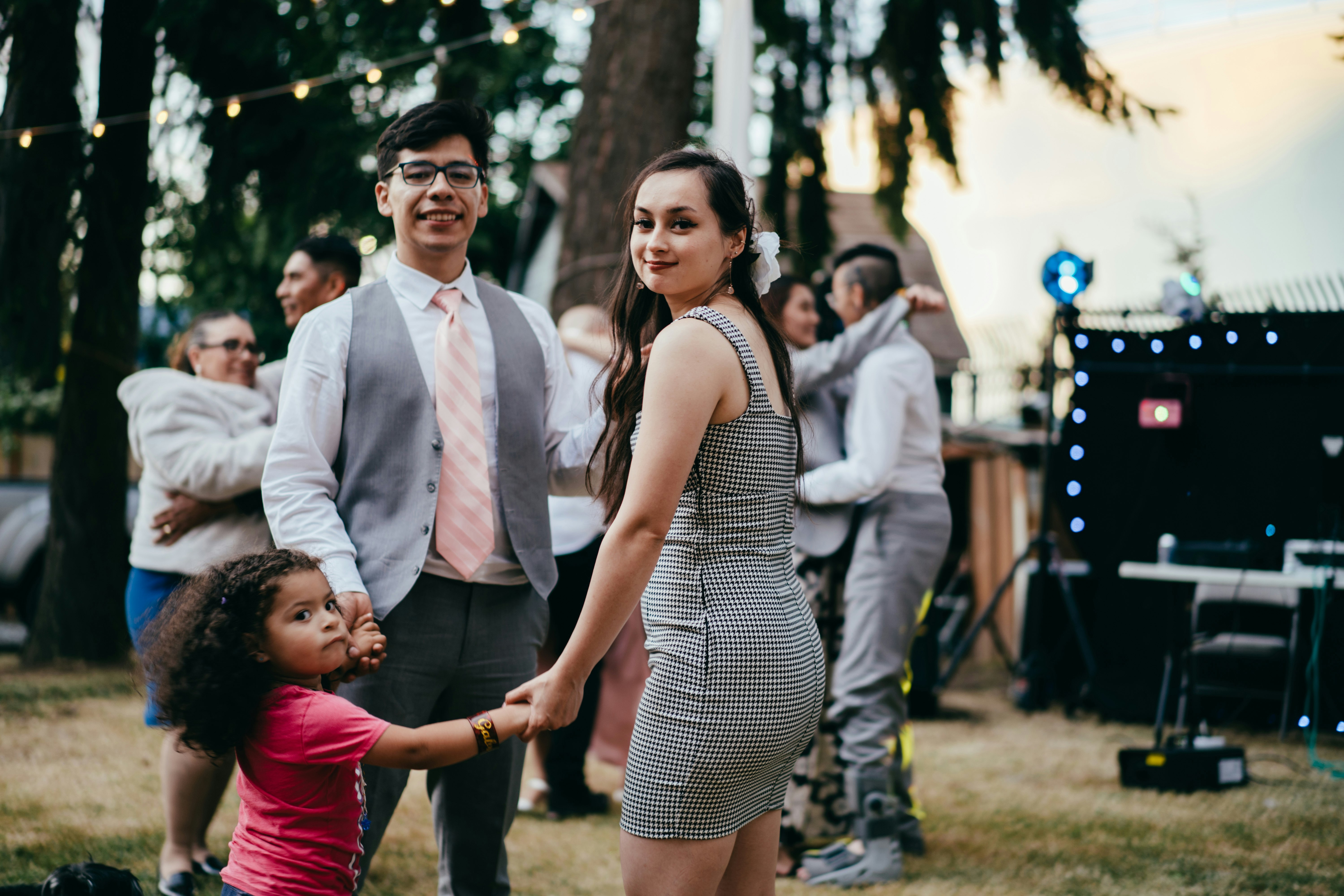 woman in black and white polka dot sleeveless dress standing beside man in white suit